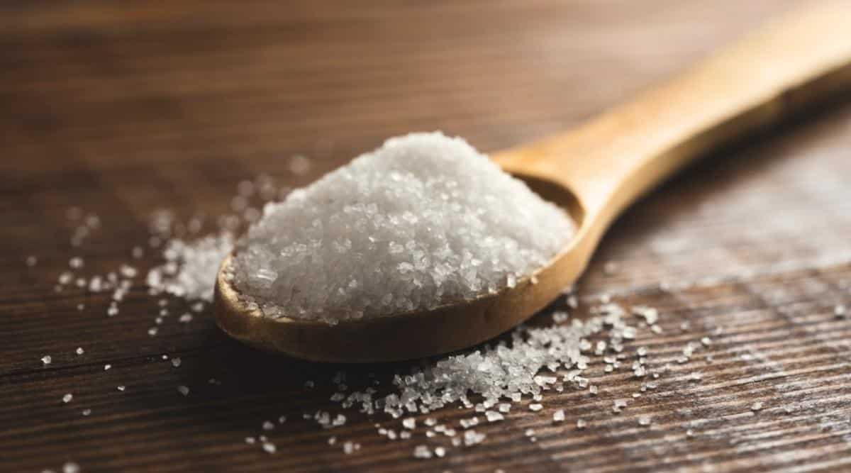 Primer plano de una cuchara de madera llena de sal de Epsom sobre una mesa marrón.  La sal de Epsom es una sal mineral, un compuesto de magnesio y sulfato en formaciones rocosas.